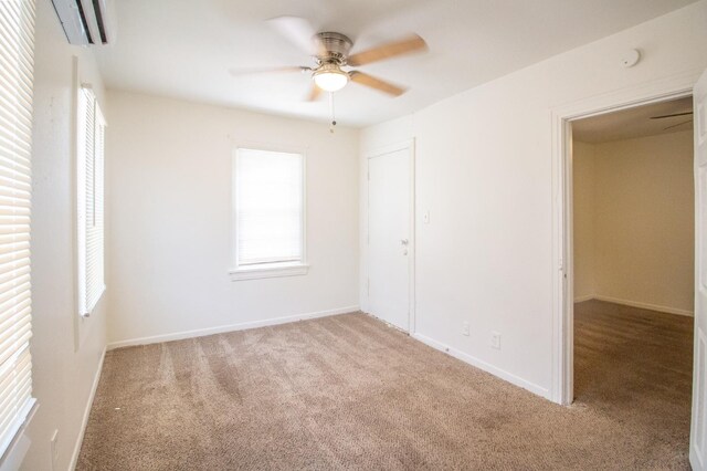 unfurnished room with ceiling fan, light colored carpet, and a wall mounted AC