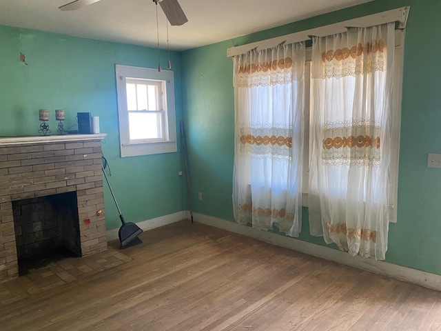 interior space featuring hardwood / wood-style floors, a brick fireplace, and ceiling fan