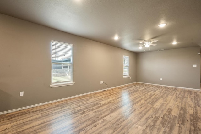 spare room with a textured ceiling, ceiling fan, and light wood-type flooring