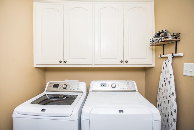 washroom featuring cabinets and washer and clothes dryer