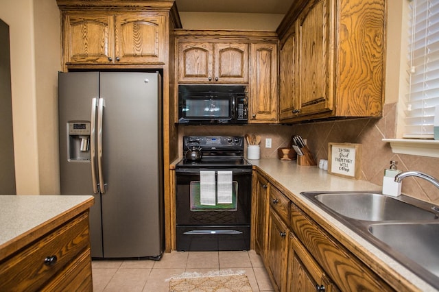 kitchen featuring sink, light tile patterned floors, decorative backsplash, and black appliances