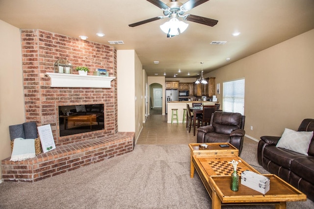 living room with a fireplace, ceiling fan, and carpet flooring