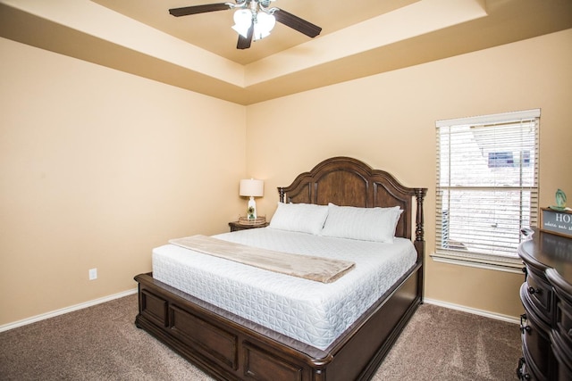 carpeted bedroom with a raised ceiling and ceiling fan