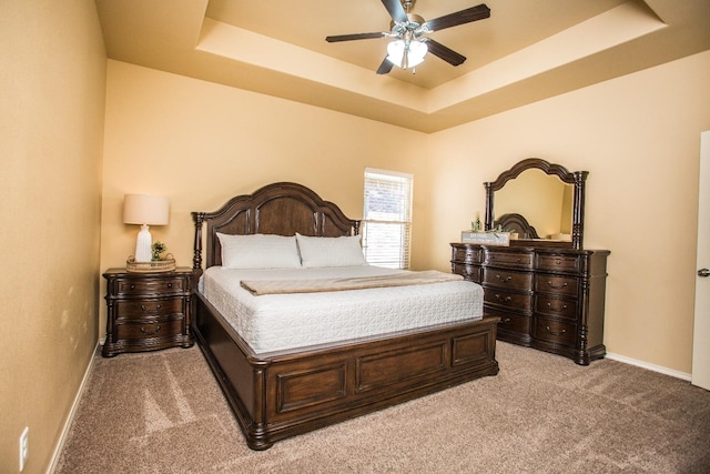 bedroom with ceiling fan, carpet flooring, and a tray ceiling