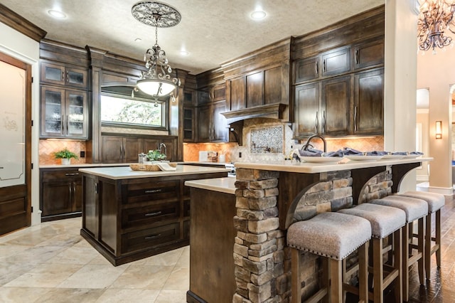 kitchen featuring a sink, light countertops, backsplash, and dark brown cabinets