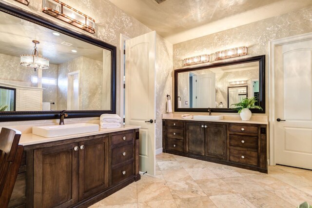 full bathroom featuring two vanities, a sink, and wallpapered walls