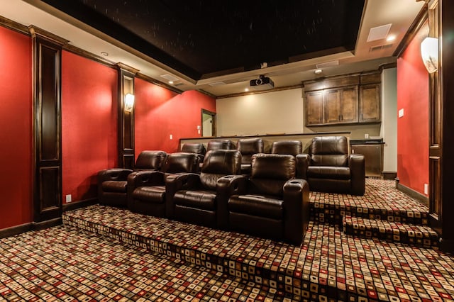 carpeted home theater room featuring baseboards and a raised ceiling