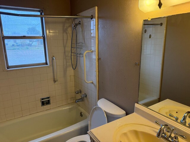 full bathroom with vanity, tiled shower / bath, a wealth of natural light, and toilet