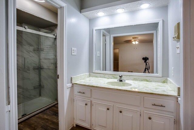 bathroom with vanity, a shower with shower door, and ceiling fan