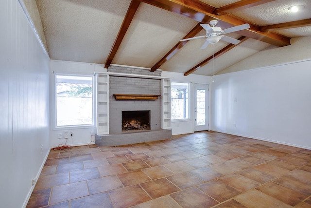 unfurnished living room featuring plenty of natural light, vaulted ceiling with beams, a fireplace, and a textured ceiling