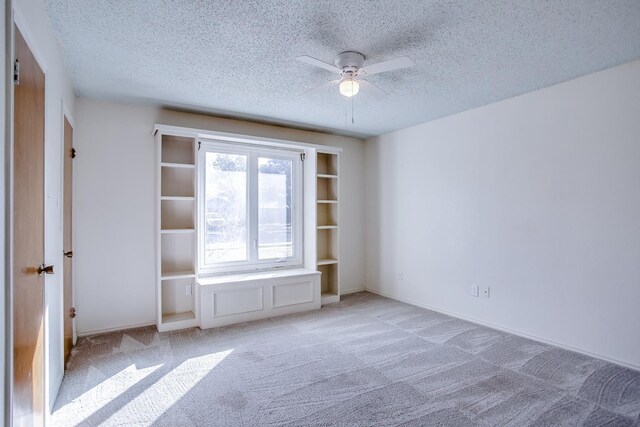 unfurnished bedroom featuring ceiling fan, light colored carpet, and a textured ceiling