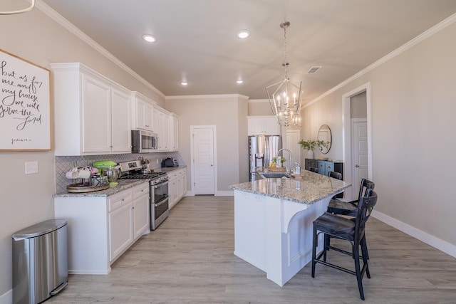 kitchen featuring a breakfast bar area, a sink, ornamental molding, stainless steel appliances, and tasteful backsplash