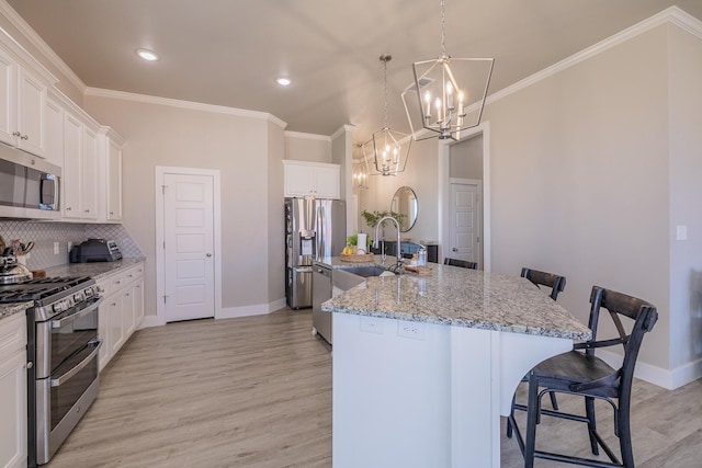 kitchen with a center island with sink, a sink, stainless steel appliances, a kitchen breakfast bar, and a notable chandelier