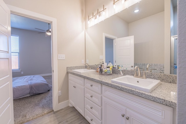 bathroom featuring double vanity, wood finished floors, baseboards, and a sink