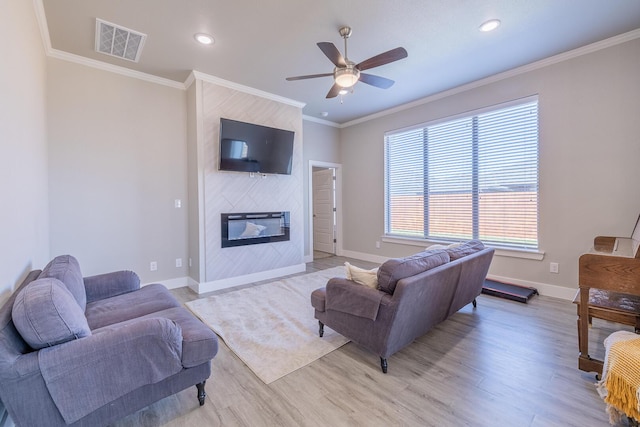 living room with visible vents, light wood-style flooring, a fireplace, and ornamental molding