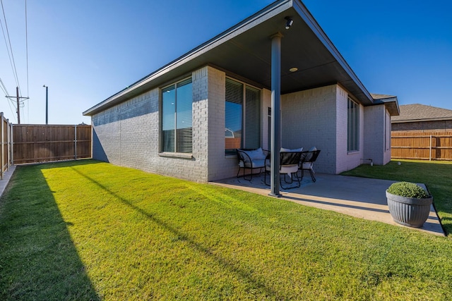 back of house featuring a yard, brick siding, a fenced backyard, and a patio area