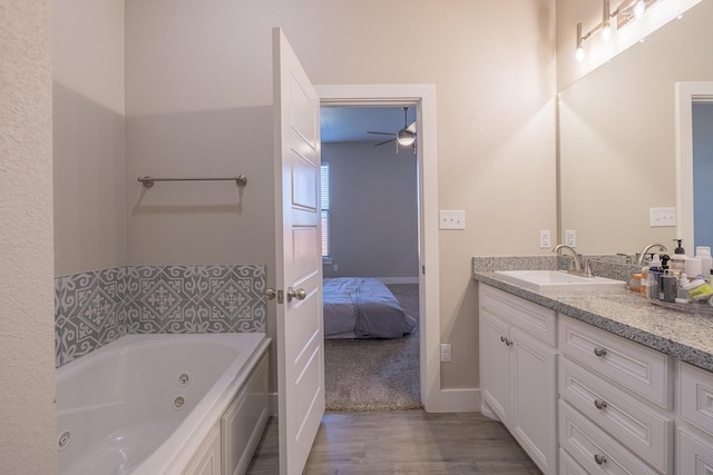 bathroom with ensuite bathroom, a whirlpool tub, wood finished floors, ceiling fan, and vanity