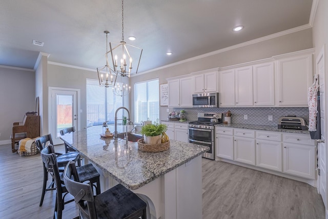 kitchen with visible vents, backsplash, light wood-style flooring, appliances with stainless steel finishes, and white cabinetry