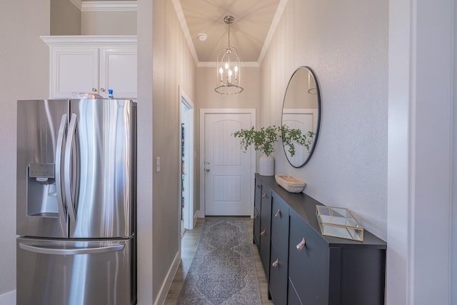 doorway with a notable chandelier, baseboards, and ornamental molding