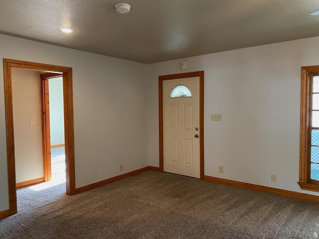 entryway featuring a healthy amount of sunlight, carpet flooring, and a textured ceiling