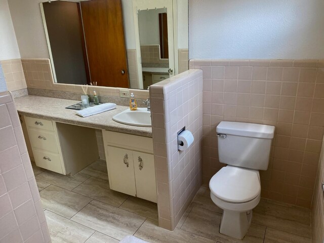 bathroom with vanity, tile patterned floors, tile walls, and toilet