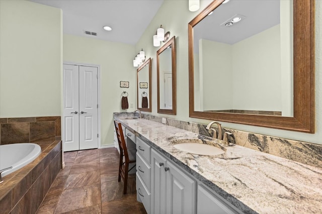 bathroom featuring double vanity, visible vents, a garden tub, and a sink