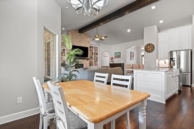 dining room featuring arched walkways, dark wood finished floors, a fireplace, and vaulted ceiling with beams