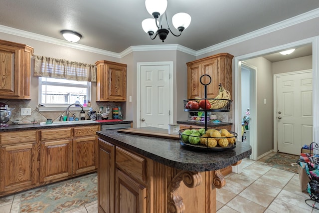 kitchen featuring dark countertops, a sink, brown cabinetry, tasteful backsplash, and crown molding