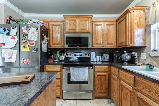 kitchen featuring stainless steel appliances, dark countertops, backsplash, crown molding, and brown cabinetry