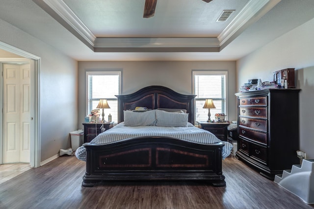 bedroom with a tray ceiling, crown molding, wood finished floors, and baseboards