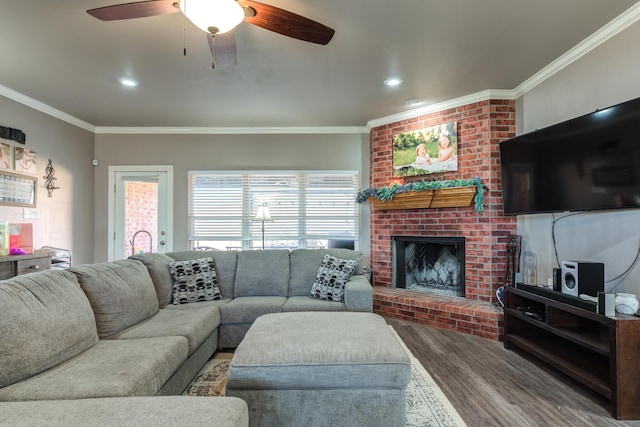 living room featuring wood finished floors, crown molding, a fireplace, a ceiling fan, and recessed lighting