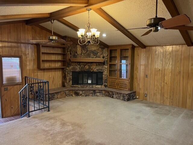 3193 US Highway 385, Littlefield, TX 79339 - unfurnished living room featuring carpet flooring, wood walls, a fireplace, ceiling fan with notable chandelier, and vaulted ceiling with beams