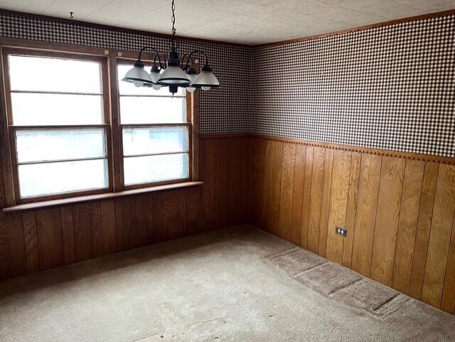 3193 US Highway 385, Littlefield, TX 79339 - unfurnished dining area with wooden walls, carpet, and a chandelier
