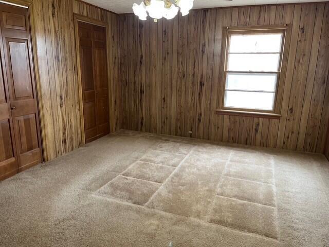 3193 US Highway 385, Littlefield, TX 79339 - unfurnished room with carpet flooring, wood walls, and an inviting chandelier
