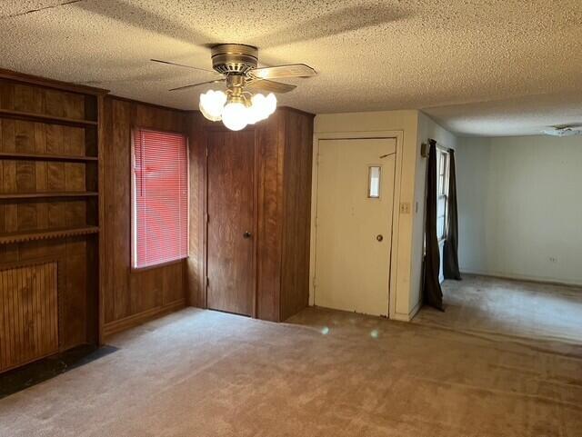 3193 US Highway 385, Littlefield, TX 79339 - interior space featuring carpet, wood walls, a textured ceiling, and ceiling fan