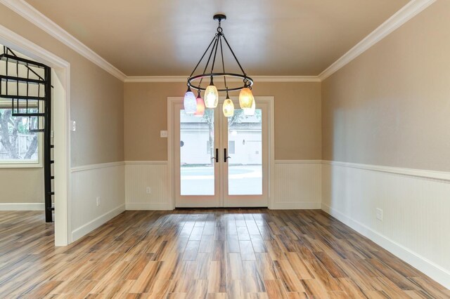 unfurnished dining area with wood-type flooring, ornamental molding, and french doors