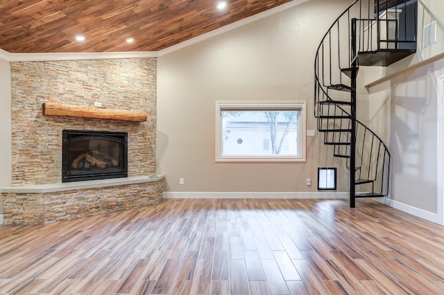 unfurnished living room featuring crown molding, a stone fireplace, hardwood / wood-style flooring, and wooden ceiling