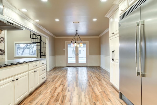 kitchen featuring pendant lighting, a healthy amount of sunlight, built in fridge, and dark stone countertops