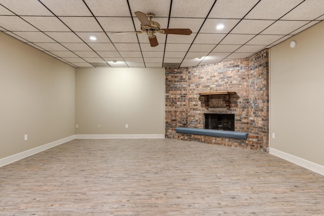 unfurnished living room featuring ceiling fan, a paneled ceiling, hardwood / wood-style floors, and a fireplace