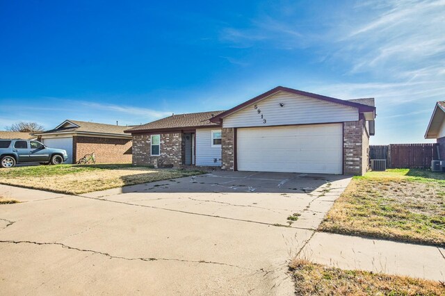 ranch-style home featuring a garage and cooling unit