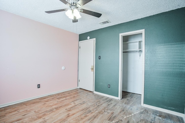 unfurnished bedroom featuring ceiling fan, a closet, a textured ceiling, and light wood-type flooring