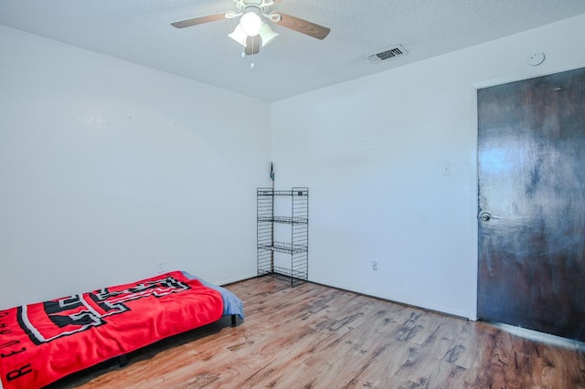 bedroom with wood-type flooring, ceiling fan, and a textured ceiling