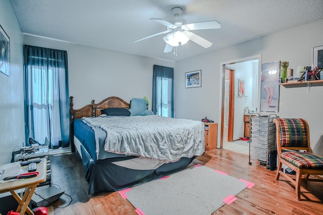 bedroom with ceiling fan, light hardwood / wood-style flooring, and a textured ceiling