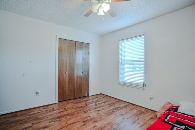 unfurnished bedroom featuring hardwood / wood-style flooring, a closet, ceiling fan, and a textured ceiling