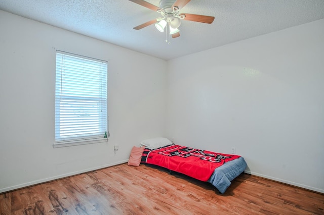 bedroom featuring hardwood / wood-style floors, a textured ceiling, and ceiling fan