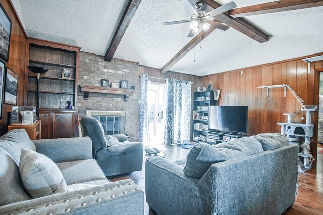 living room featuring dark hardwood / wood-style flooring, a brick fireplace, a textured ceiling, and wood walls