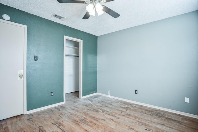 unfurnished bedroom featuring a closet, ceiling fan, a textured ceiling, and light hardwood / wood-style flooring