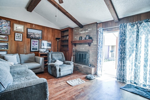 living room with hardwood / wood-style floors, vaulted ceiling with beams, a textured ceiling, and wood walls