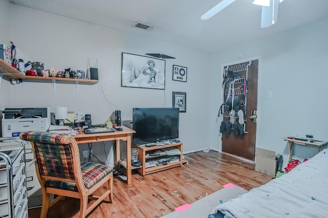 bedroom with ceiling fan, a textured ceiling, and light hardwood / wood-style floors