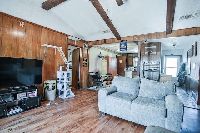 living room featuring ceiling fan, wood-type flooring, lofted ceiling with beams, and a textured ceiling